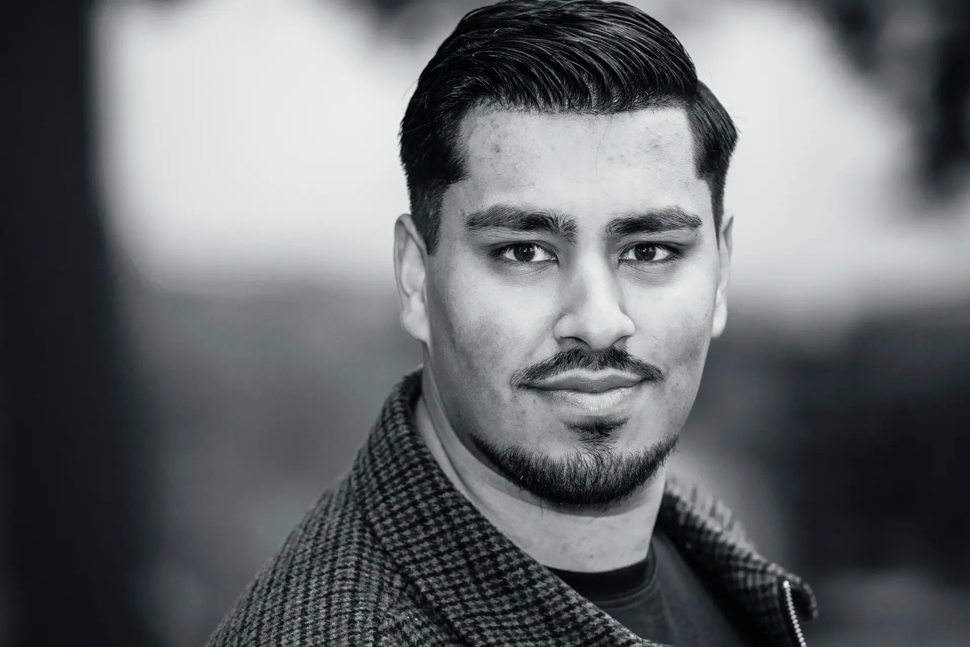 Zwart-wit headshot van Zubaid Shah in een geruit jasje